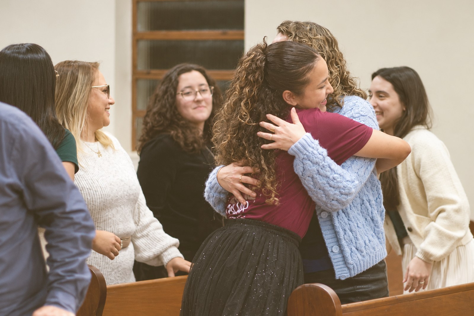 Pessoas se acolhendo em comunhão na igreja, imagem ilustrativa
